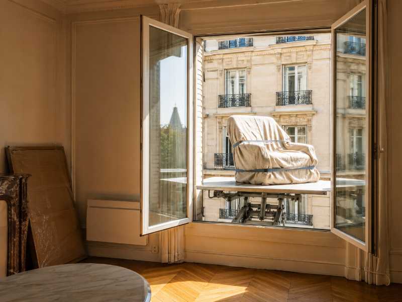 Passage d’un meuble par la fenêtre d’un étage élevé sur le plateau d’un monte-meuble